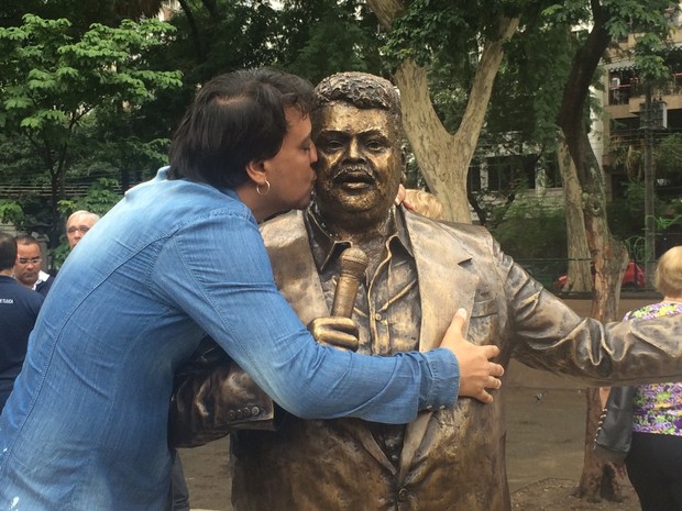 Carmelo Maia, filho de Tim, beija a estátua do pai. Foto: Matheus Rodrigues/G1 Rio
