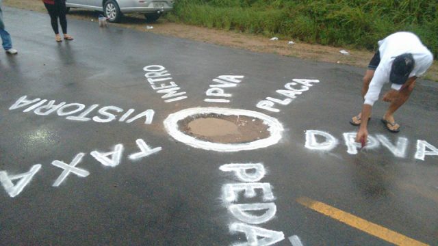 Manifestantes escreveram, em um dos buracos, nomes dos impostos que pagam Foto: Reprodução/ Facebook Geremias Palmeira