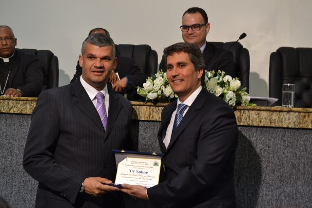 O vereador Pablo Roberto entrega a Marcos Araújo, gerente geral, uma placa em homenagem à emissora. Foto: Olá Bahia