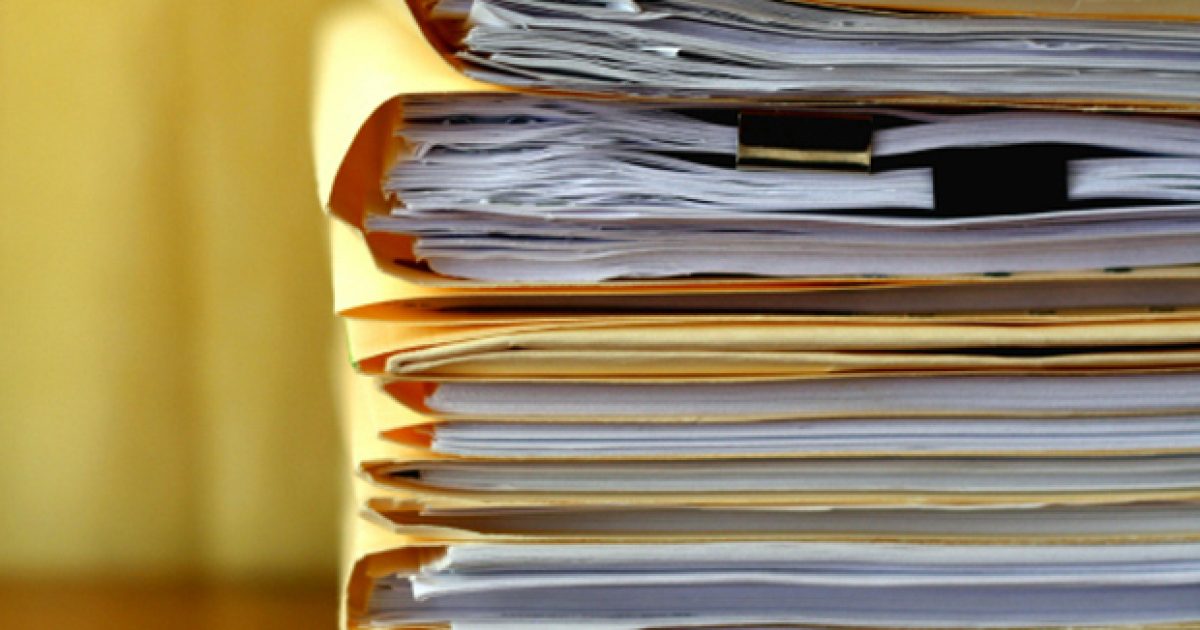 Manila file folders stacked on a desk.