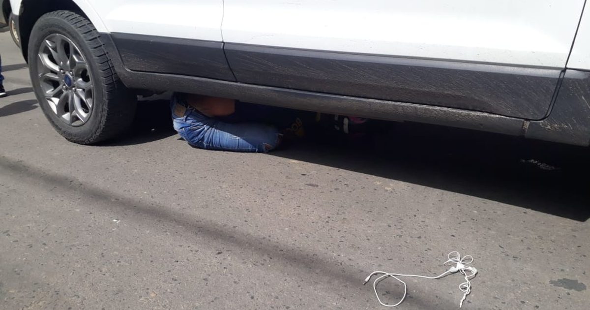 O homem aparece quase que sentando embaixo do carro, a centímetros do pneu traseiro do veículo. ( Foto: Divulgação/Corpo de Bombeiros)