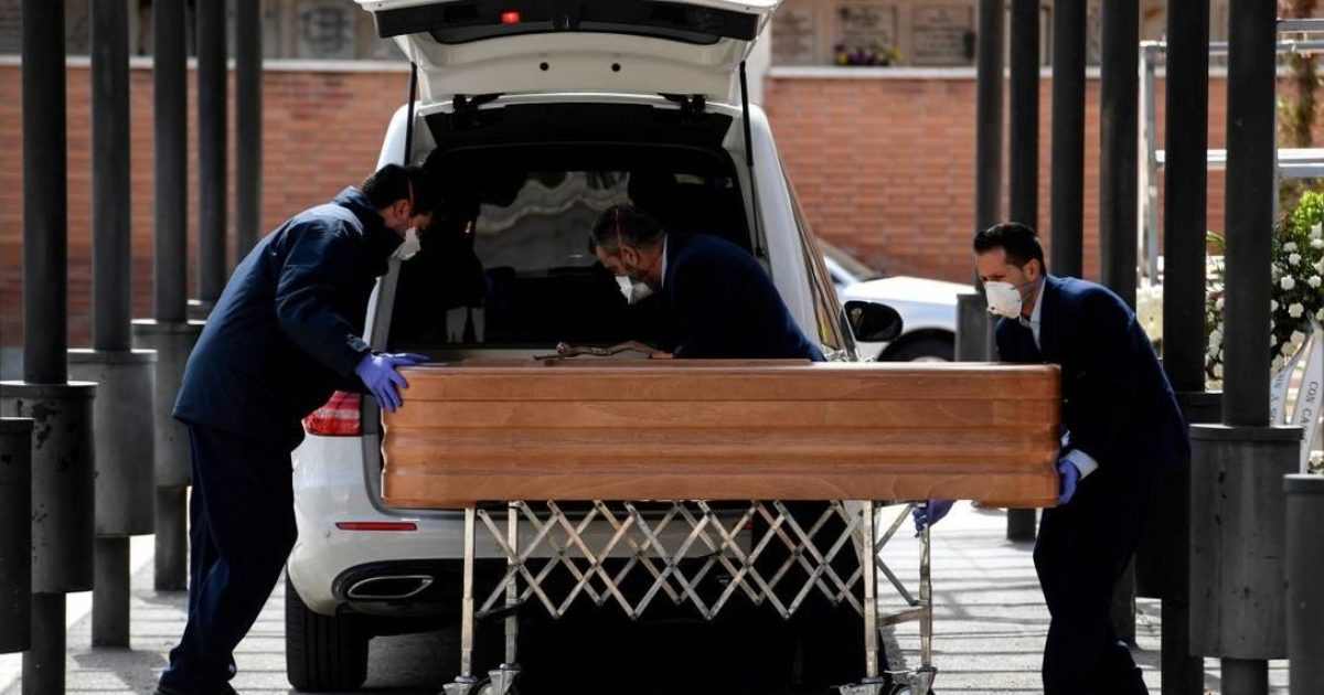 Funcionários de uma funerária levam caixão de vítima da Covid-19 para crematório Foto: OSCAR DEL POZO / AFP